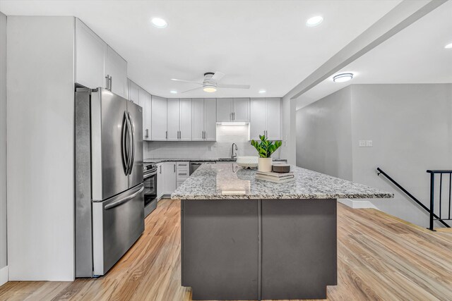 3631 Bower Rd, Roanoke, VA 24018 - kitchen featuring stainless steel appliances, a kitchen island, light wood finished floors, a ceiling fan, and light stone counters