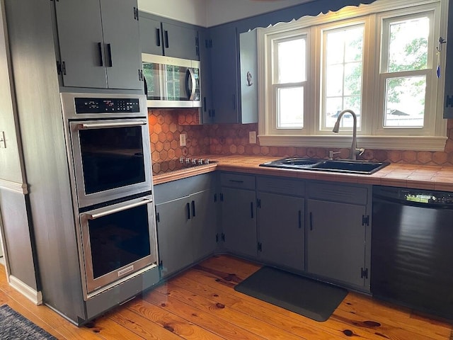 3210 Orchard Hill Rd SW, Roanoke, VA 24018 - kitchen with stainless steel appliances, tasteful backsplash, tile countertops, and light wood-type flooring