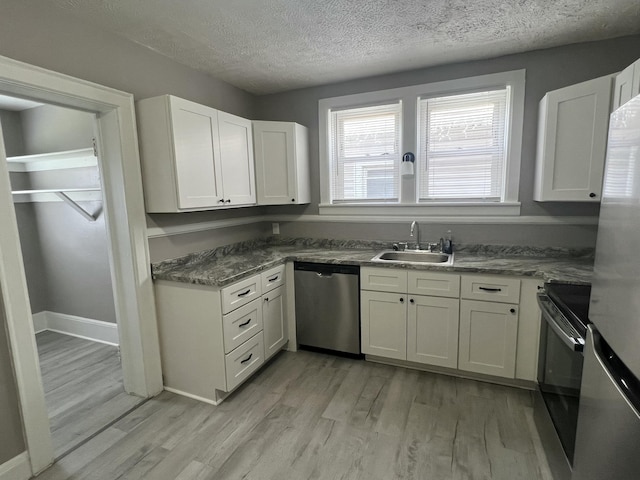115 E Walnut St, Covington, VA 24426 - kitchen featuring appliances with stainless steel finishes, light wood finished floors, white cabinetry, and a textured ceiling