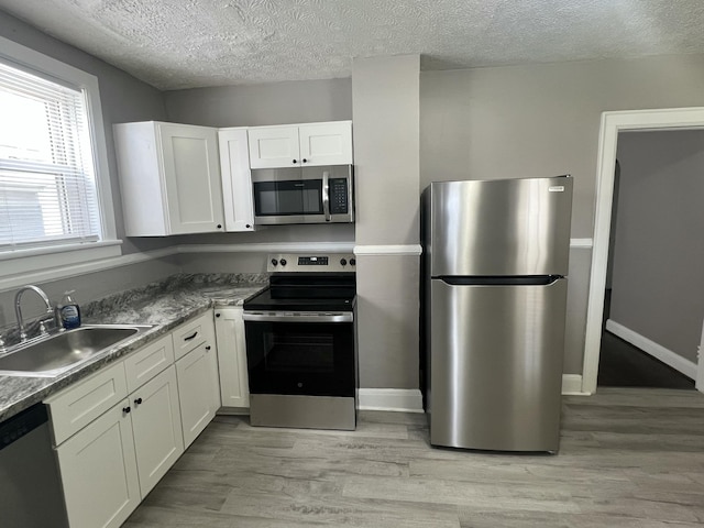 115 E Walnut St, Covington, VA 24426 - kitchen with appliances with stainless steel finishes, a textured ceiling, white cabinets, and light wood finished floors