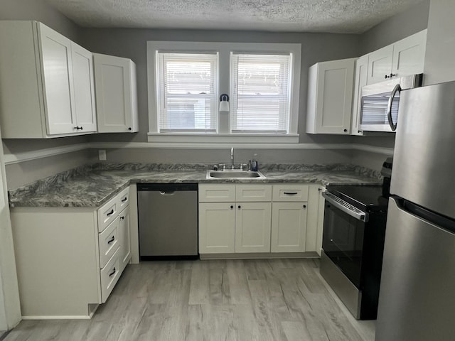 115 E Walnut St, Covington, VA 24426 - kitchen featuring stainless steel appliances, a textured ceiling, light wood-style flooring, and white cabinets