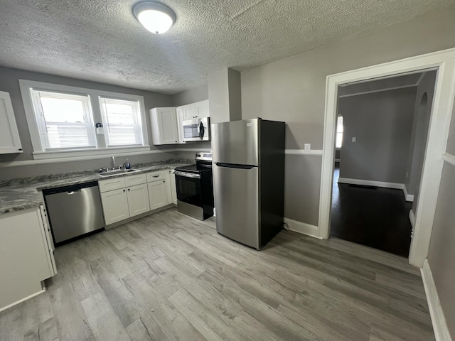 115 E Walnut St, Covington, VA 24426 - kitchen featuring stainless steel appliances, a textured ceiling, light wood-type flooring, and white cabinetry