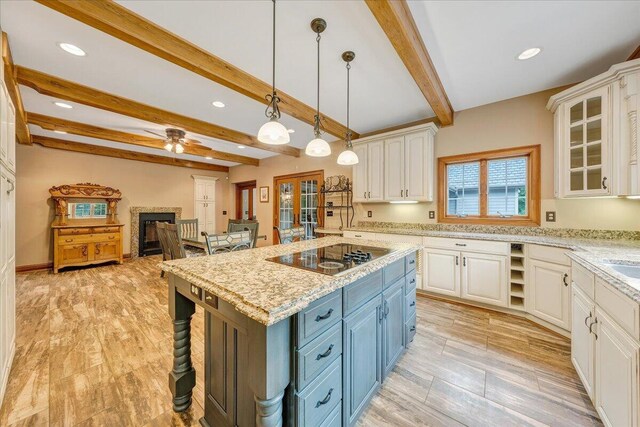 223 Moonriver Ln, Moneta, VA 24121 - kitchen featuring blue cabinets, black electric cooktop, white cabinets, beamed ceiling, and a fireplace