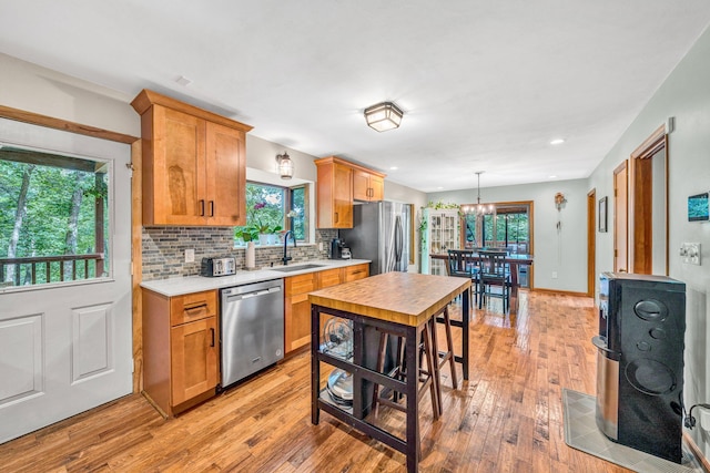 7102 Crown Rd, Roanoke, VA 24018 - kitchen with appliances with stainless steel finishes, light countertops, a chandelier, light wood-style floors, and decorative backsplash