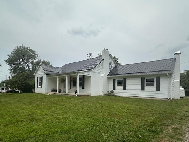 2327 Horsepasture Price Rd, Ridgeway, VA 24148 - rear view of house with a chimney, a lawn, a metal roof, and covered porch