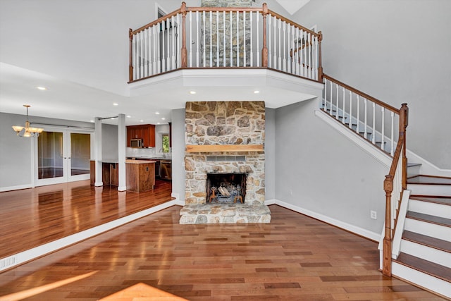 571 Cary Rd, Pilot, VA 24138 - unfurnished living room with wood finished floors, a chandelier, stairs, a high ceiling, and a stone fireplace