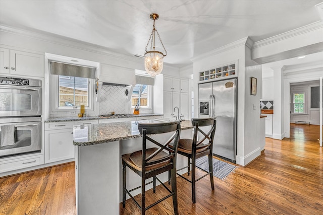 2410 Cornwallis Ave SE, Roanoke, VA 24014 - kitchen featuring stainless steel appliances, light wood-type flooring, tasteful backsplash, a breakfast bar, and dark stone countertops