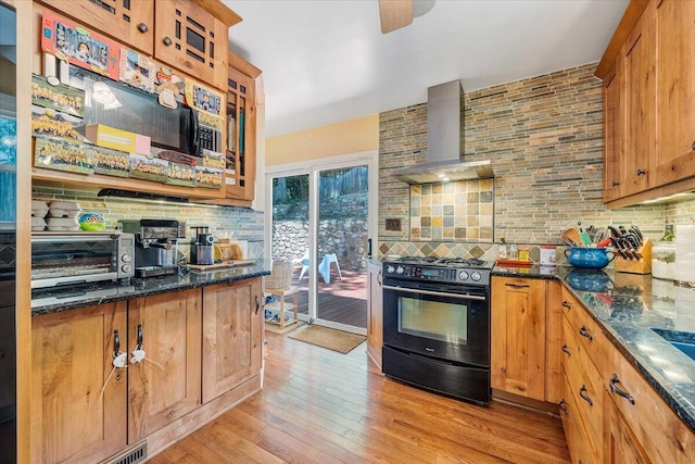 2702 Yellow Mountain Rd SE, Roanoke, VA 24014 - kitchen featuring black range with gas stovetop, wall chimney exhaust hood, backsplash, light wood-style floors, and dark stone counters