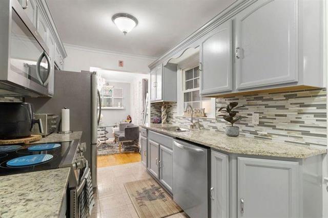 3325 Fleetwood Ave SW, Roanoke, VA 24015 - kitchen with appliances with stainless steel finishes, backsplash, ornamental molding, and light stone counters