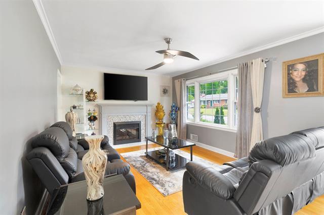 3325 Fleetwood Ave SW, Roanoke, VA 24015 - living room with crown molding, a ceiling fan, light wood finished floors, and a glass covered fireplace