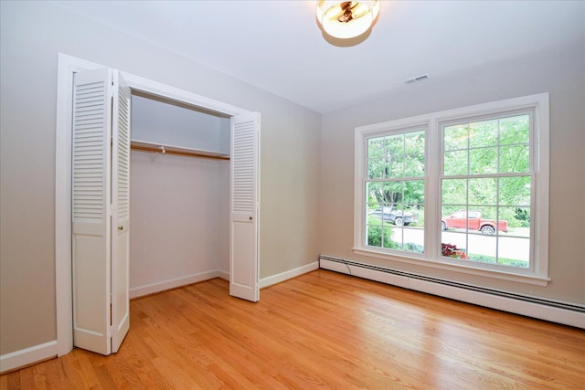 115 Bartley Dr, Salem, VA 24153 - unfurnished bedroom featuring a baseboard heating unit, multiple windows, light wood finished floors, and a closet