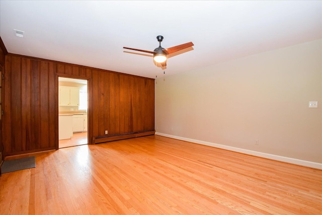 115 Bartley Dr, Salem, VA 24153 - spare room featuring a baseboard heating unit, ceiling fan, light wood-style floors, and wood walls