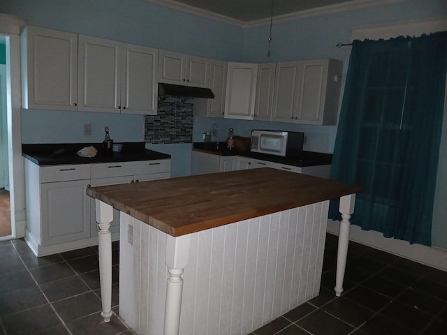 918 Dale Ave SE, Roanoke, VA 24013 - kitchen with white microwave, ornamental molding, under cabinet range hood, butcher block countertops, and dark tile patterned floors