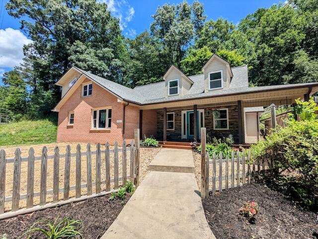 221 Camp Creek Rd NW, Riner, VA 24149 - view of front of house featuring a porch, a fenced front yard, and brick siding
