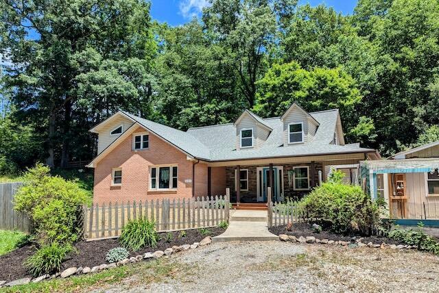 221 Camp Creek Rd NW, Riner, VA 24149 - new england style home featuring a porch, a fenced front yard, and brick siding
