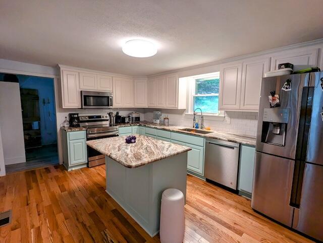 221 Camp Creek Rd NW, Riner, VA 24149 - kitchen featuring appliances with stainless steel finishes, a kitchen island, tasteful backsplash, light wood-style floors, and white cabinets