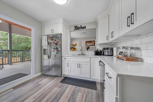 901 Samantha Cir, Roanoke, VA 24019 - kitchen with appliances with stainless steel finishes, light wood-type flooring, white cabinets, backsplash, and light countertops