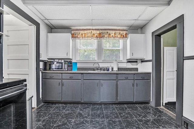 1831 S Carpenter Dr, Covington, VA 24426 - kitchen featuring a drop ceiling, gray cabinets, dark countertops, stove, and white cabinets