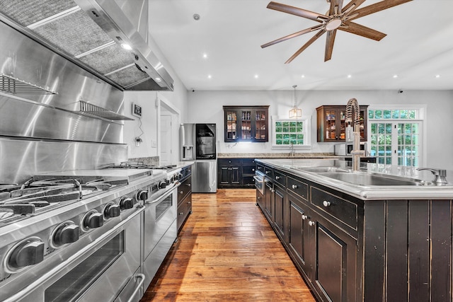 3150 Green Ridge Rd NW, Roanoke, VA 24019 - kitchen featuring stainless steel appliances, wall chimney exhaust hood, glass insert cabinets, light countertops, and light wood-style floors