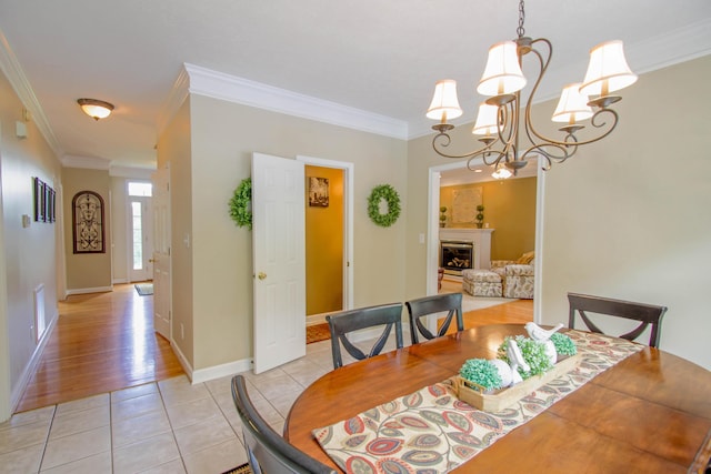 1266 Wills Way, Forest, VA 24551 - dining space with crown molding, light tile patterned floors, a chandelier, and a glass covered fireplace