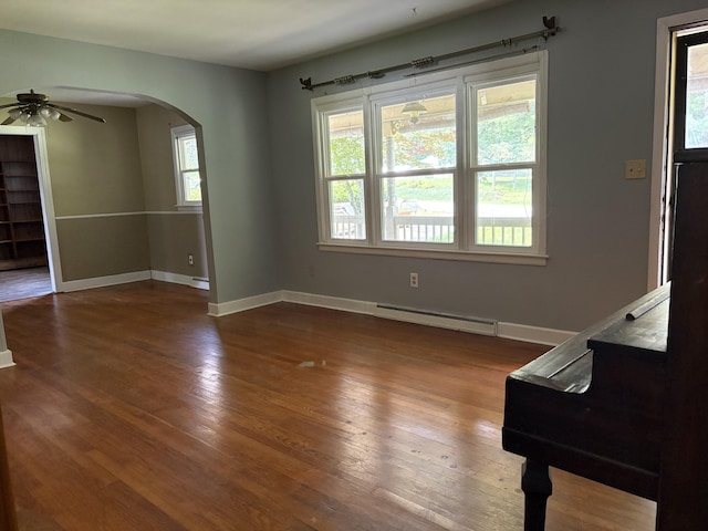 713 Rose Ave, Covington, VA 24426 - empty room featuring a baseboard heating unit, arched walkways, a ceiling fan, wood finished floors, and stairway