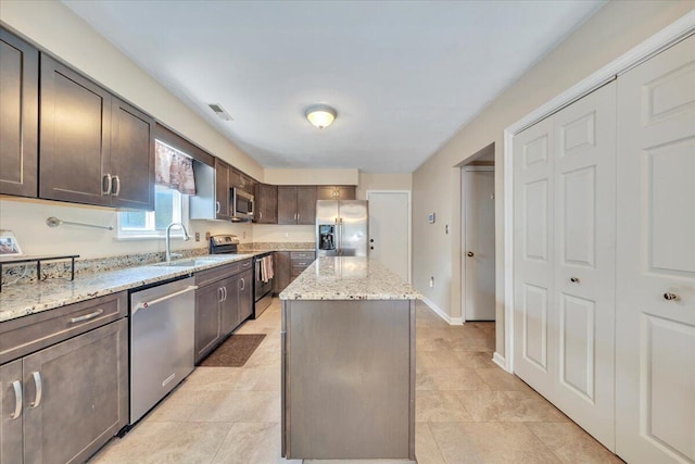 3341 Fort Lewis Cir, Salem, VA 24153 - kitchen featuring appliances with stainless steel finishes, a center island, dark brown cabinetry, light stone countertops, and light tile patterned floors