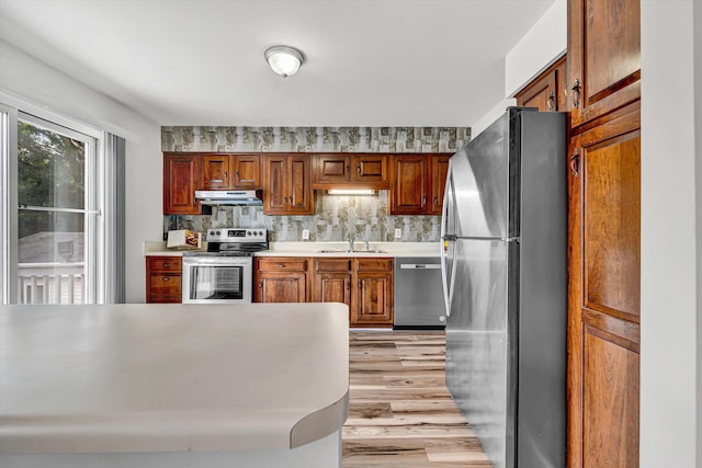 3716 Bower Rd, Roanoke, VA 24018 - kitchen with appliances with stainless steel finishes, under cabinet range hood, light countertops, light wood-type flooring, and brown cabinets