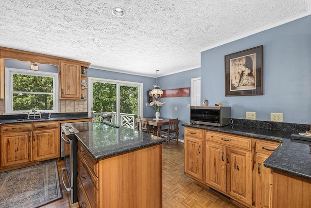 420 Cresthill Rd, Lynchburg, VA 24504 - kitchen featuring appliances with stainless steel finishes, ornamental molding, brown cabinetry, a kitchen island, and a textured ceiling