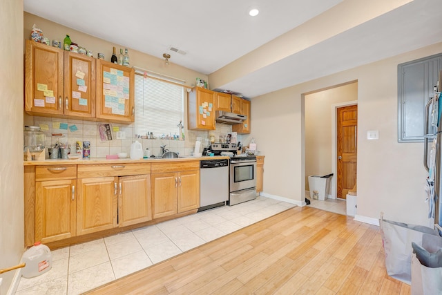 1406 Melrose Ave NW, Roanoke, VA 24017 - kitchen with appliances with stainless steel finishes, tasteful backsplash, light wood finished floors, under cabinet range hood, and light countertops