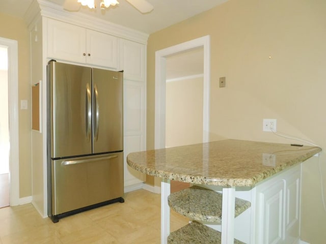 4029 Kentland Dr, Roanoke, VA 24018 - kitchen featuring freestanding refrigerator, a peninsula, white cabinetry, a kitchen bar, and light stone counters