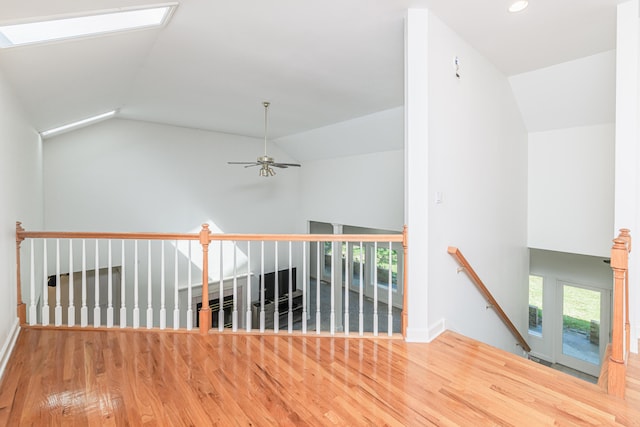 corridor with vaulted ceiling with skylight and hardwood / wood-style floors