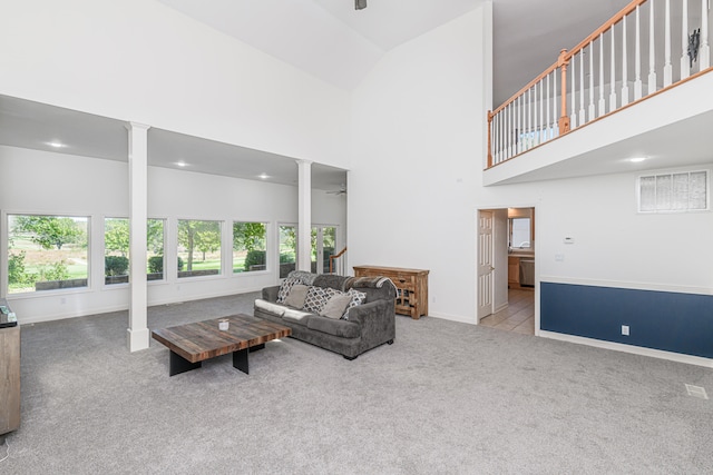 living room with high vaulted ceiling, decorative columns, light colored carpet, and ceiling fan