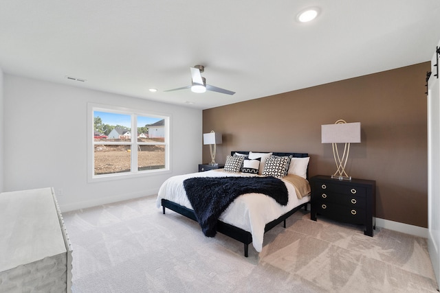 carpeted bedroom featuring ceiling fan and a barn door