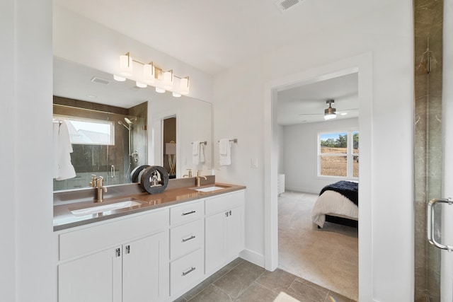 bathroom with dual sinks, tile floors, vanity with extensive cabinet space, ceiling fan, and an enclosed shower