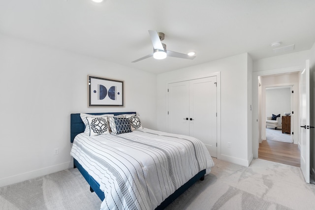 bedroom featuring light colored carpet, a closet, and ceiling fan