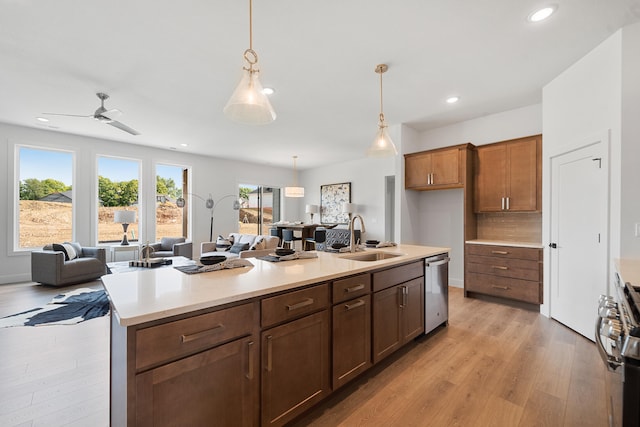 kitchen featuring decorative light fixtures, backsplash, ceiling fan, sink, and light wood-type flooring