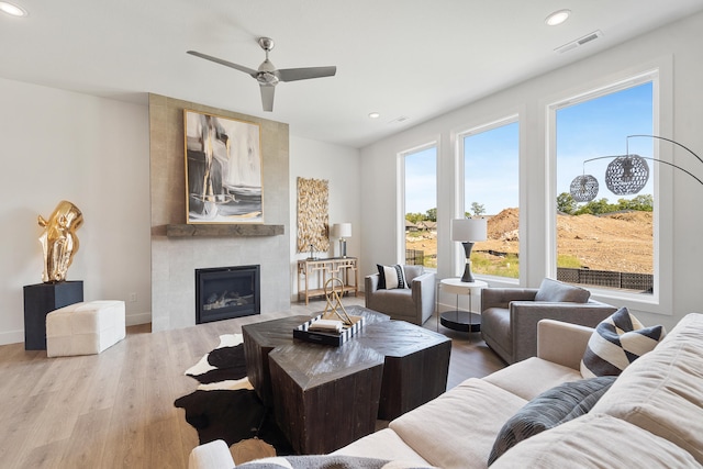 living room featuring ceiling fan, a fireplace, and wood-type flooring