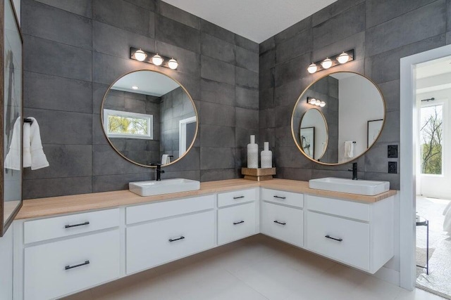 bathroom with tile walls, a wealth of natural light, tile floors, and vanity with extensive cabinet space