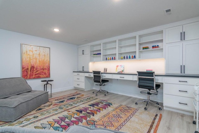 office area with built in desk and light wood-type flooring