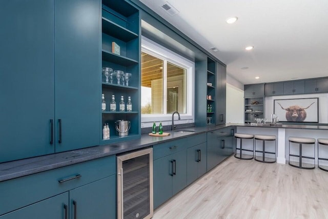 bar featuring beverage cooler, light hardwood / wood-style flooring, and sink