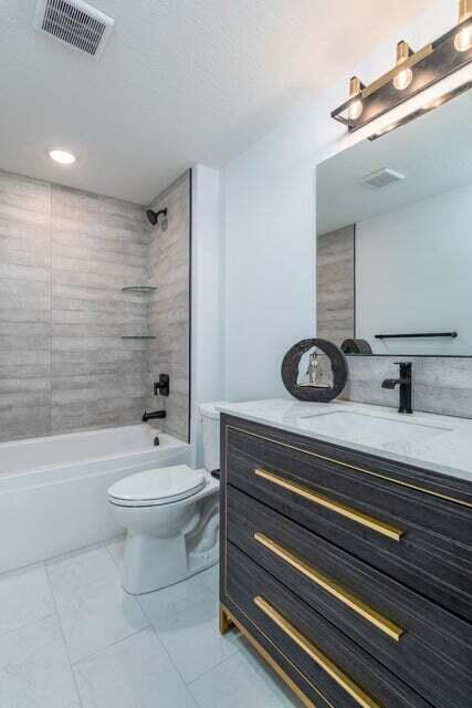 full bathroom with tiled shower / bath combo, tile flooring, toilet, and vanity