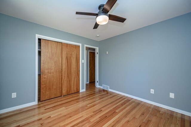 unfurnished bedroom with a closet, baseboards, wood finished floors, and ceiling fan