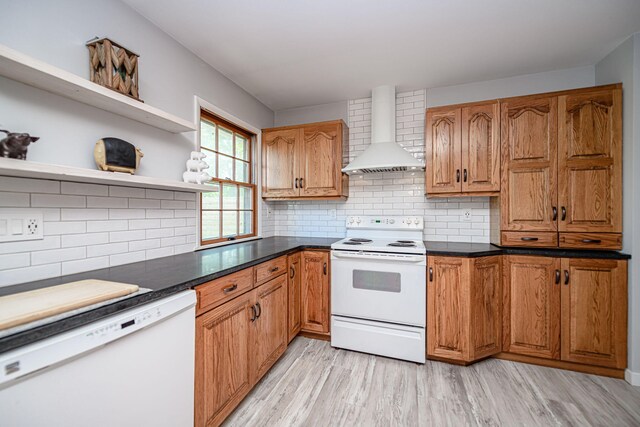 kitchen featuring white appliances, wall chimney range hood, light wood finished floors, open shelves, and backsplash