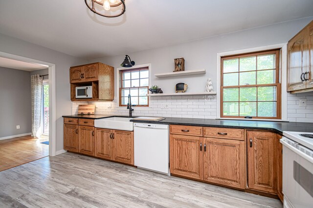 kitchen featuring white appliances, a sink, light wood-type flooring, and brown cabinetry