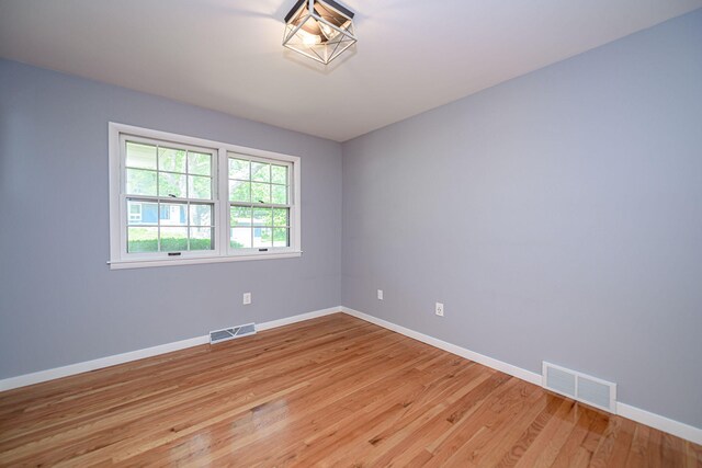 spare room with baseboards and light wood finished floors