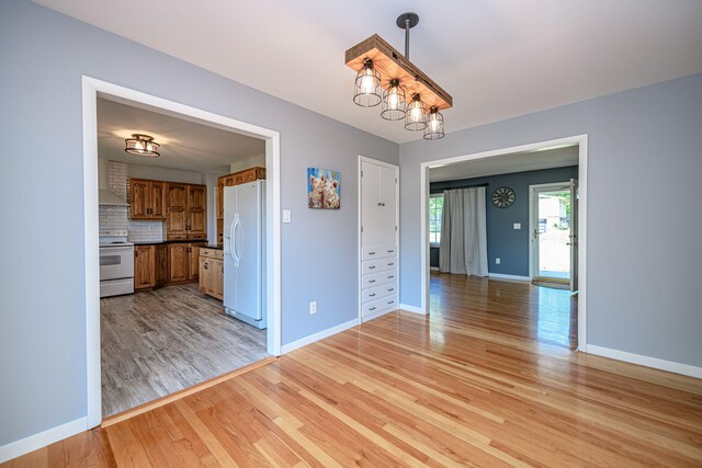 unfurnished dining area with light wood finished floors and baseboards