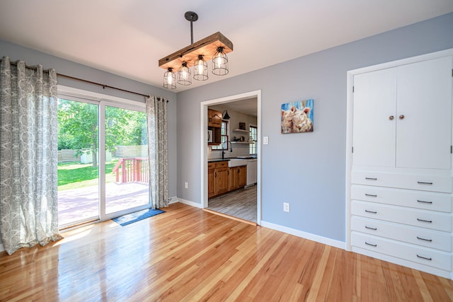 unfurnished dining area with light wood-style flooring, baseboards, and a chandelier