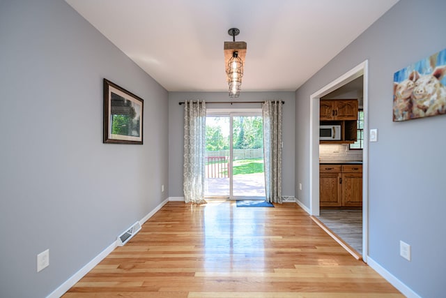 unfurnished dining area featuring light wood-style floors and baseboards