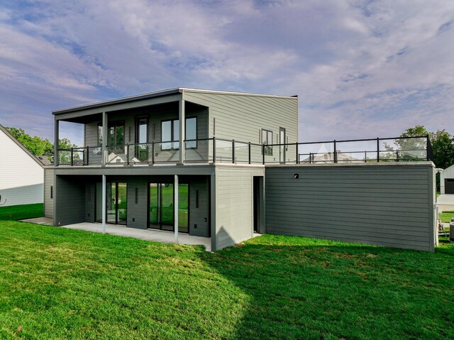 back of house featuring a patio, a lawn, and a balcony