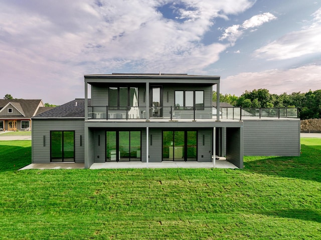 rear view of property featuring a patio, a balcony, and a lawn